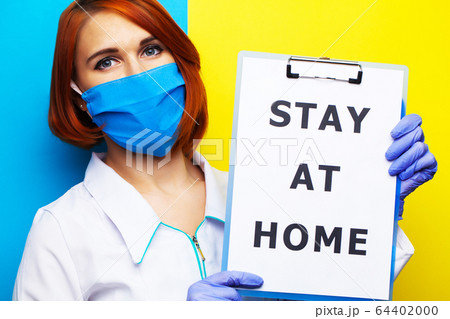 Woman holding blank with inscription stay at home calling for stop spreading covid-19. 64402000