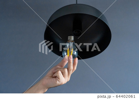Close-up. A hand changes a light bulb in a stylish 64402061
