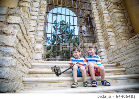 Two cute little brothers sitting on stairs in 64406483