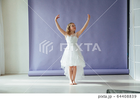 Girl in a dress dances to the music alone in the room 64408839