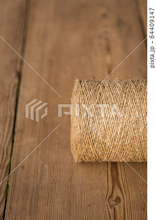 A roll of twine on a wooden background. Selelective focus. Close-up. Free space for text. A roll of twine on a wooden background. Selelective focus. Close-up. Free space for text. 64409147