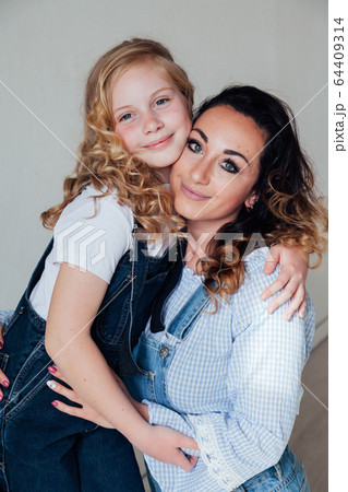 beautiful mother and daughter in denim clothes in a white room beautiful mother and daughter in denim clothes in a white room 64409314