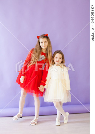 two girl girlfriends in red and white dresses on a purple background 64409337