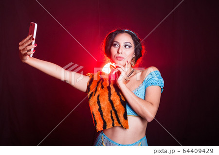Girl doing selfie with tiger skin, crazy photos. Don't eco friendly lifestyle. Young woman takes pictures of herself in the phone. Life in social networks, narcissism, modern personality. Personality 64409429