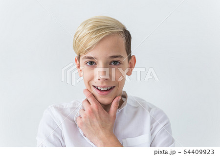 Close-up of teen boy with braces on teeth smiling on white background. Dentistry and teenager concept. 64409923