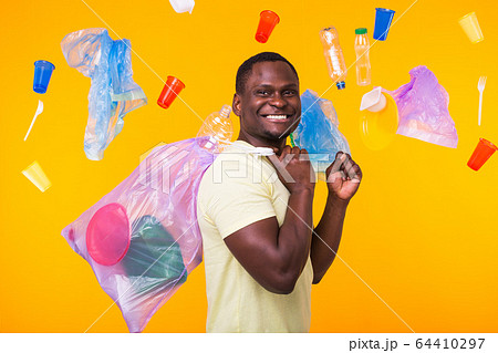 Problem of trash, plastic recycling, pollution and environmental concept - funny man carrying garbage bag on yellow background Problem of trash, plastic recycling, pollution and environmental concept - funny man carrying garbage bag on yellow background 64410297