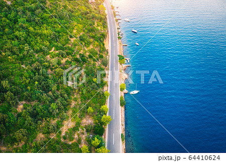Aerial view of road in beautiful green forest and boats in the sea at sunset in summer. landscape 64410624