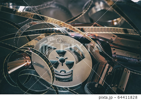 Old coil with 8 mm of film on vintage dark background of cinema strips, photographic films, retro style. Photo, movie, cinema concept 64411828