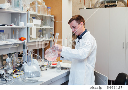 male scientist conducts chemical experiments with liquids in science lab male scientist conducts chemical experiments with liquids in science lab 64411874