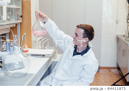 male scientist conducts chemical experiments with liquids in science lab male scientist conducts chemical experiments with liquids in science lab 64411875