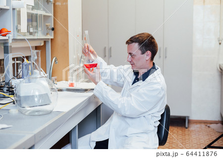 male scientist conducts chemical experiments with liquids in science lab male scientist conducts chemical experiments with liquids in science lab 64411876