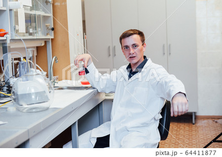male scientist conducts chemical experiments with liquids in science lab male scientist conducts chemical experiments with liquids in science lab 64411877
