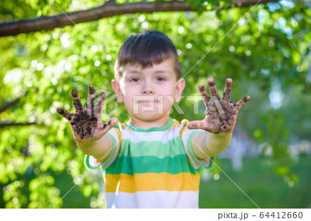 A young Caucasian boy showing off his dirty hands A young Caucasian boy showing off his dirty hands 64412660