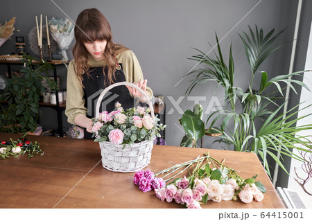 Floral shop concept . Florist woman creates flower arrangement in a wicker basket. Beautiful bouquet of mixed flowers. Handsome fresh bunch. Flowers delivery. 64415001