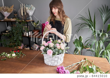 Floral shop concept . Florist woman creates flower arrangement in a wicker basket. Beautiful bouquet of mixed flowers. Handsome fresh bunch. Flowers delivery. 64415010