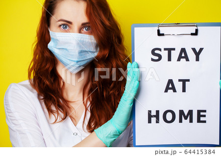 Woman holding blank with inscription stay at home calling for stop spreading covid-19. 64415384