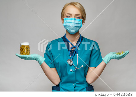 medical doctor nurse woman wearing protective mask and rubber or latex gloves - holding can of pills medical doctor nurse woman wearing protective mask and rubber or latex gloves - holding can of pills 64423638