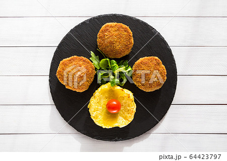 Homemade burgers or cutlets with baked formed potatoes and salad on stone plate and wooden table. Homemade burgers or cutlets with baked formed potatoes and salad on stone plate and wooden table. 64423797