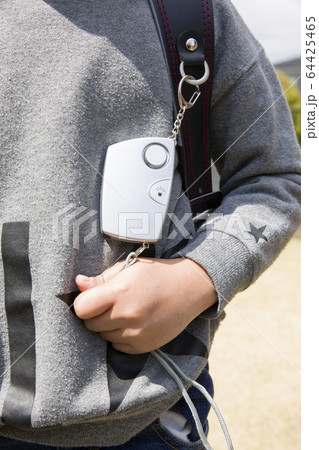 防犯ブザーを握り締める小学生男の子手元 64425465