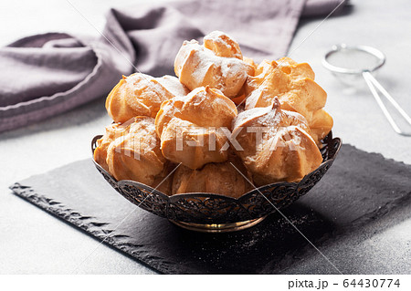 Profiteroles with custard and powdered sugar on a Profiteroles with custard and powdered sugar on a 64430774