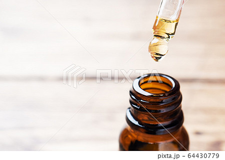Drop falls from the pipette. Bottle of cosmetic 64430779