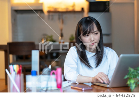 深夜まで自宅で仕事をする若い女性 深夜まで自宅で仕事をする若い女性 64432878