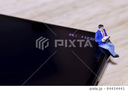 バッテリー残量不足のスマートフォンと読書する男性 64434441