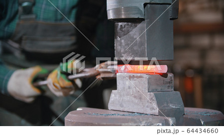 Forging an item out of hot iron using a pressure machine Forging an item out of hot iron using a pressure machine 64434660