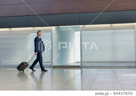 Mature businessman walking with his suitcase in 64437650