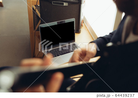 Caucasian musician playing guitar during concert at home isolated and quarantined, cheerful improvising, focus on blank laptop screen Caucasian musician playing guitar during concert at home isolated and quarantined, cheerful improvising, focus on blank laptop screen 64439237