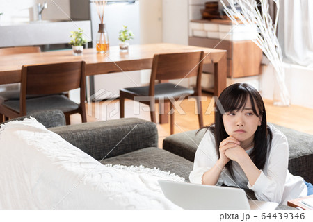 リビングで考え込む若い女性 リビングで考え込む若い女性 64439346
