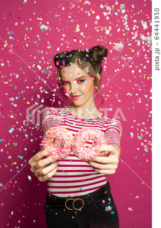 Woman with sweets in confetti on vivid pink 64441950