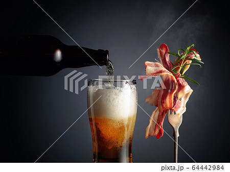 Beer and slices of tasty fried bacon garnished 64442984