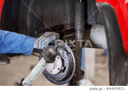 Rusty drum brakes, rear on red car. Change the old to new brake disc on car in a garage. Auto mechanic repairing 64445621