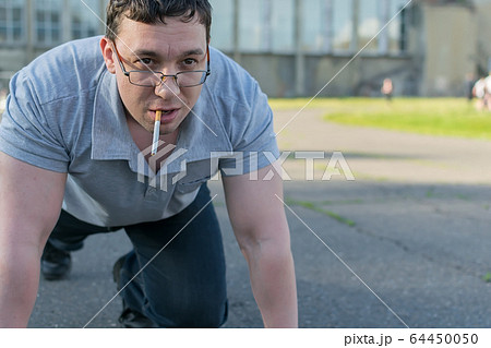 a man with a cigarette stands at the stadium in the start stand 64450050