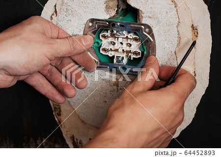 Replacing and installing a new electrical outlet. Hands with a screwdriver male electrician Replacing and installing a new electrical outlet. Hands with a screwdriver male electrician 64452893