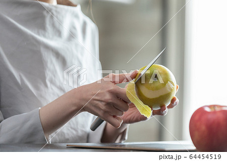 部屋の中でりんごの皮を剥く若い女性の手元の写真素材