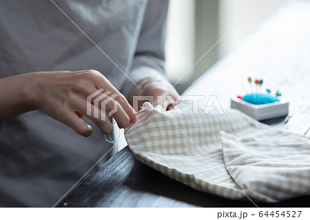 部屋の中で裁縫をする若い女性の手元 64454527