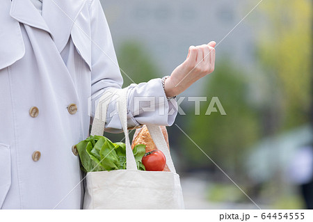 スーパーマーケットで買物した食品をエコバッグに入れてもつ若い女性の手元 64454555