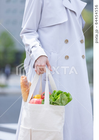 スーパーマーケットで買物した食品をエコバッグに入れてもつ若い女性の手元 64454556