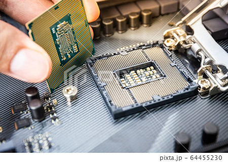 Closeup detail of CPU Chip over socket with hand of a modern computer black motherboard. Electronic small component details. Select focus 64455230