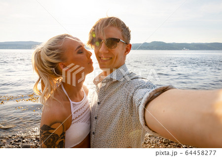 Happy Young Man Taking Selfie With Girlfriend At Beach 64458277