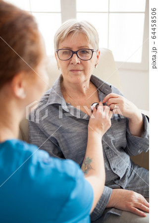 Back view of female nurse using stethoscope in nursing home Back view of female nurse using stethoscope in nursing home 64458506