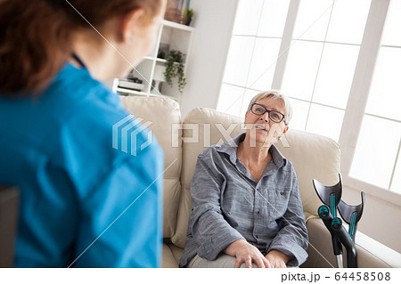 Back view of female health visitor talking with old woman Back view of female health visitor talking with old woman 64458508