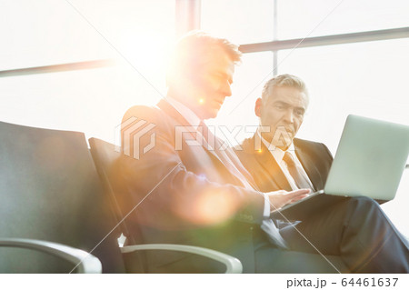 Mature businessman reading news paper while the Mature businessman reading news paper while the 64461637