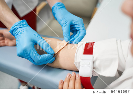 Professional medical worker putting plaster on arm Professional medical worker putting plaster on arm 64461697