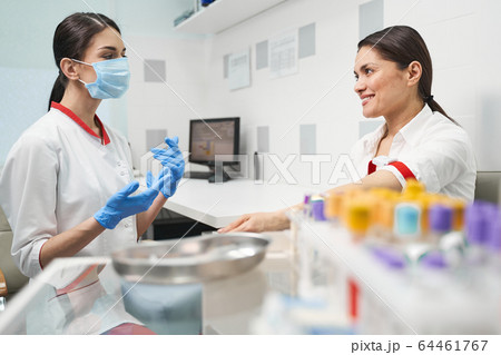 Positive delighted young woman giving sample of blood Positive delighted young woman giving sample of blood 64461767