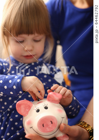 Child little girl arm putting coins into piggybank Child little girl arm putting coins into piggybank 64462792