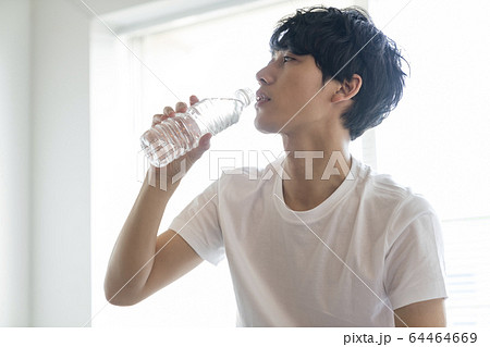 ペットボトルの水を飲む若い男性の写真素材