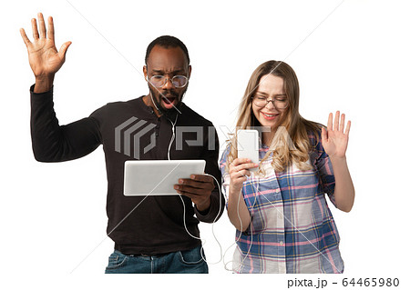 Emotional man and woman using gadgets on white studio background, technologies connecting people. Gaming, shopping, online meeting 64465980